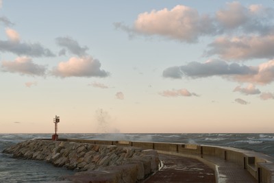 Red lighthouse with waves at sunset