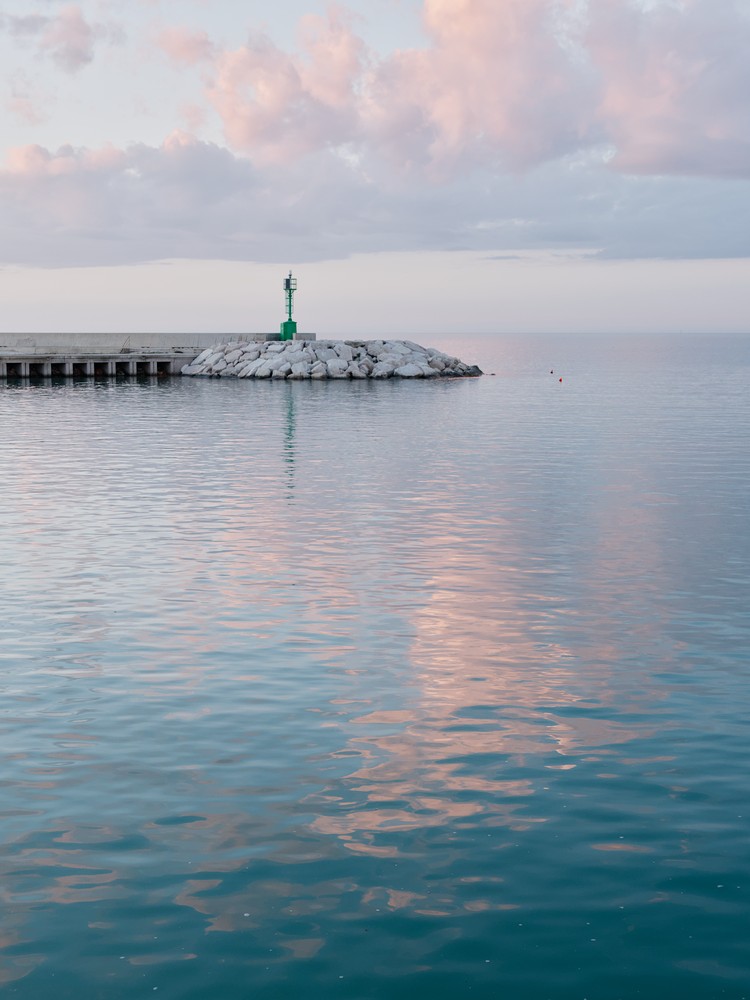 Green lighthouse with clouds reflection