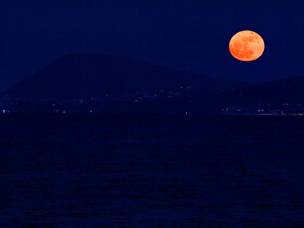 Red moon over Mount Conero at night